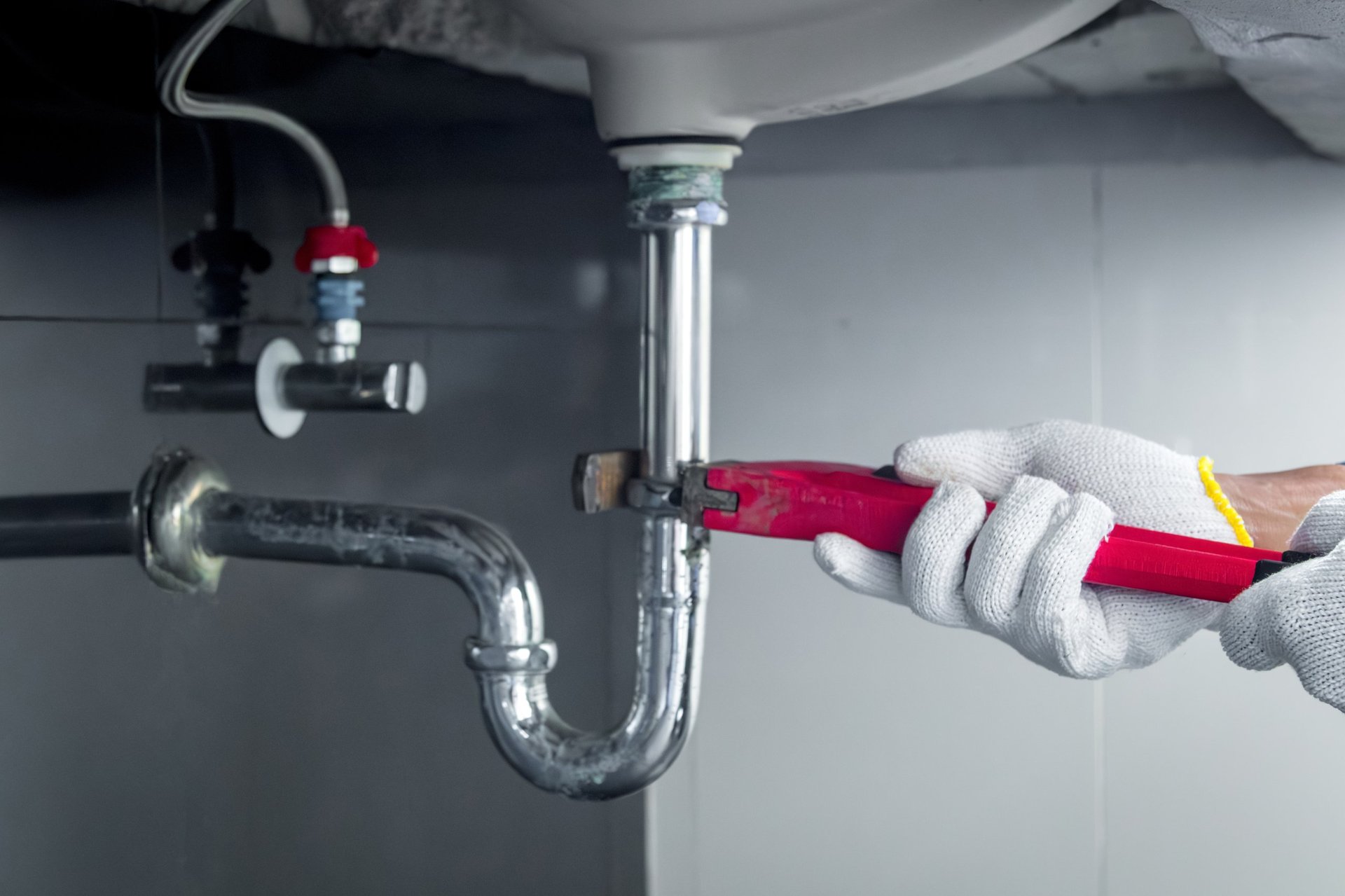 Plumber hands holding wrench doing repairing work at the sink and clogged pipe in bathroom carefully